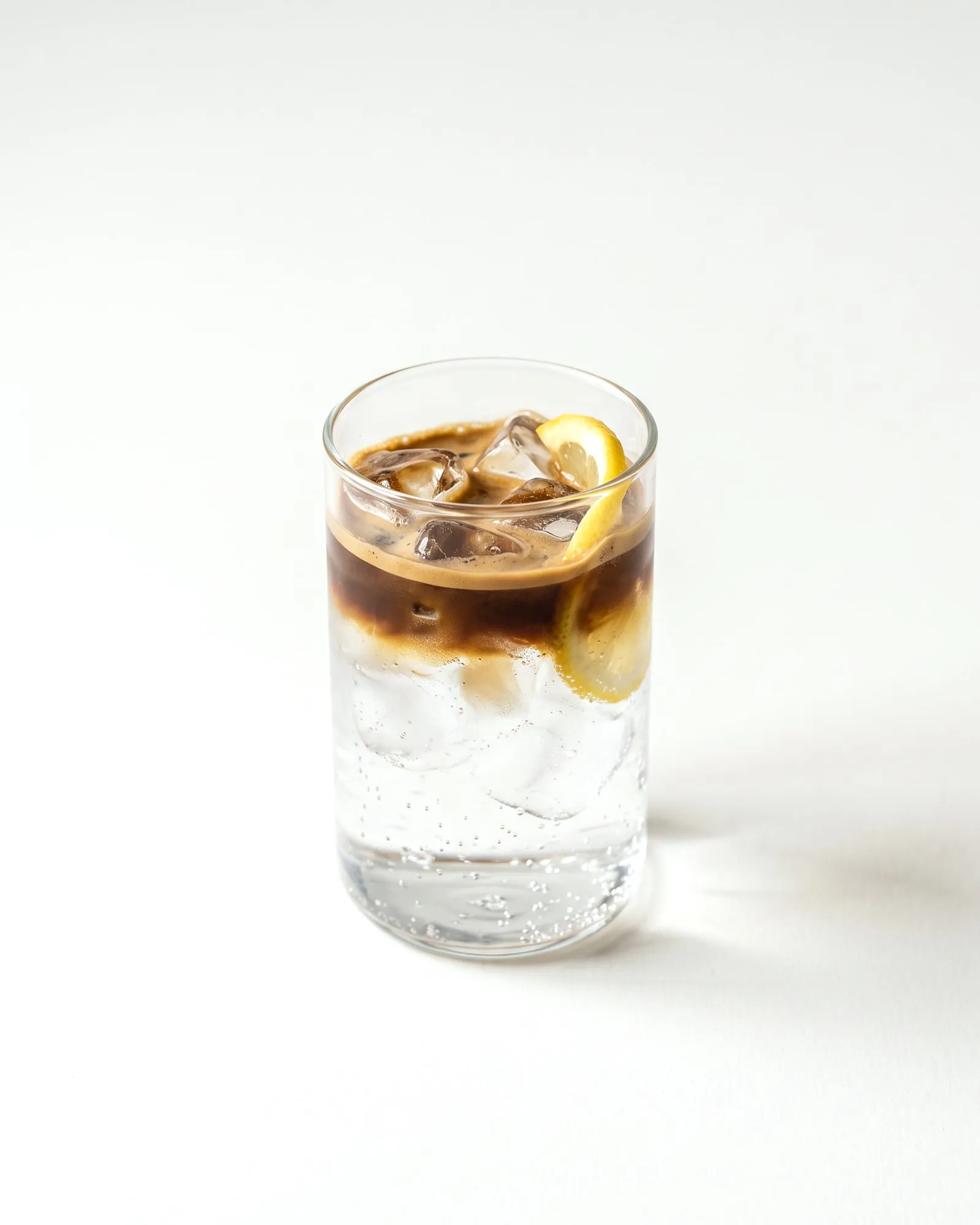 Espresso tonic en vaso de vidrio con hielo y una rodaja de limón