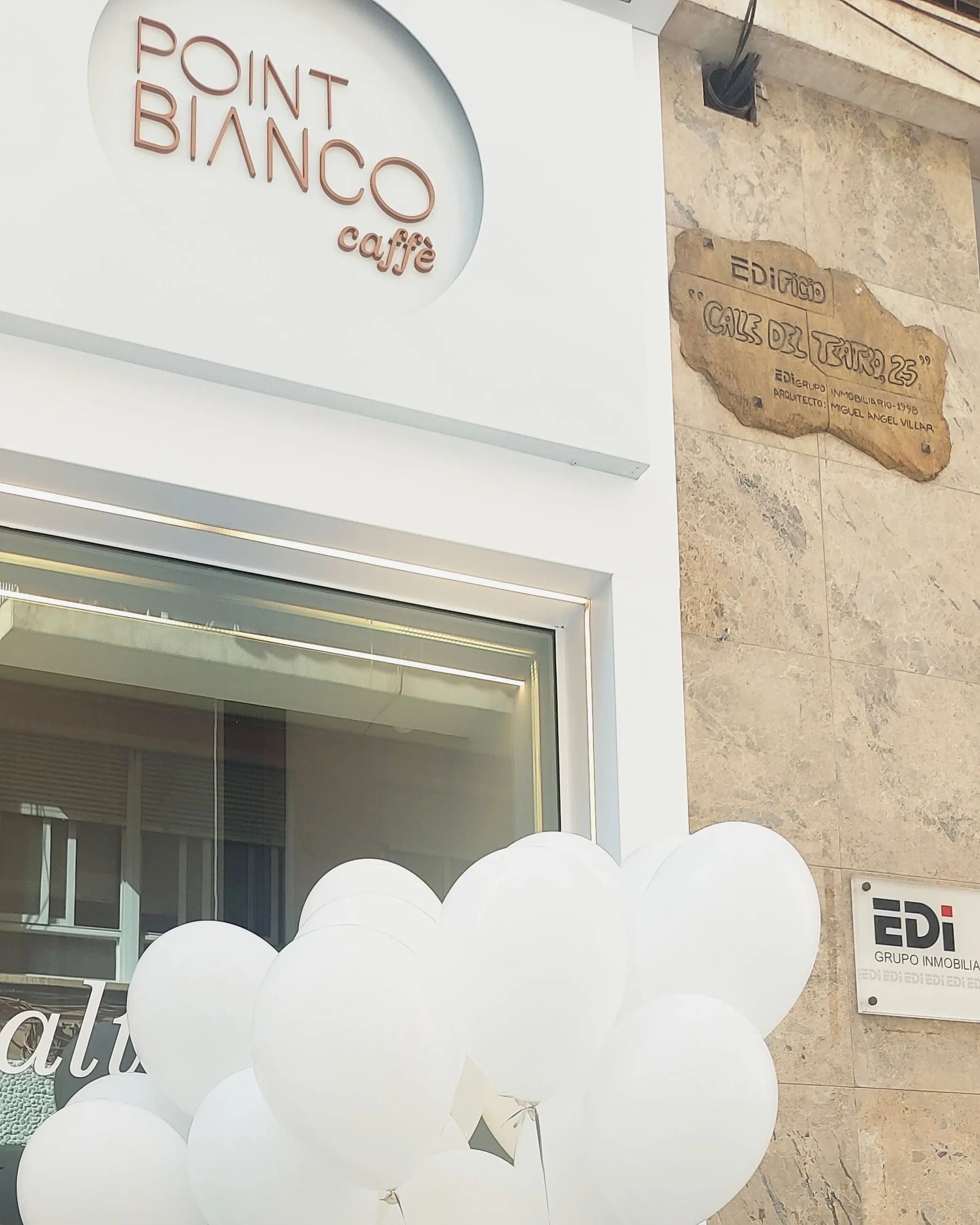 Entrada de Point Bianco en la calle del Teatro, con el rótulo «Point Bianco caffè» y globos blancos